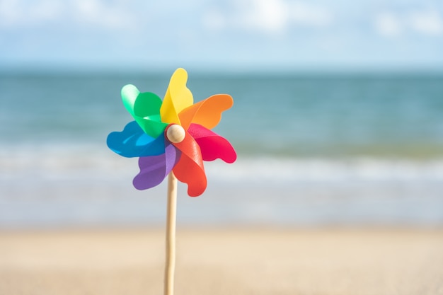 Carta colorata mulino a vento ricamato sulla spiaggia vista mare di giorno