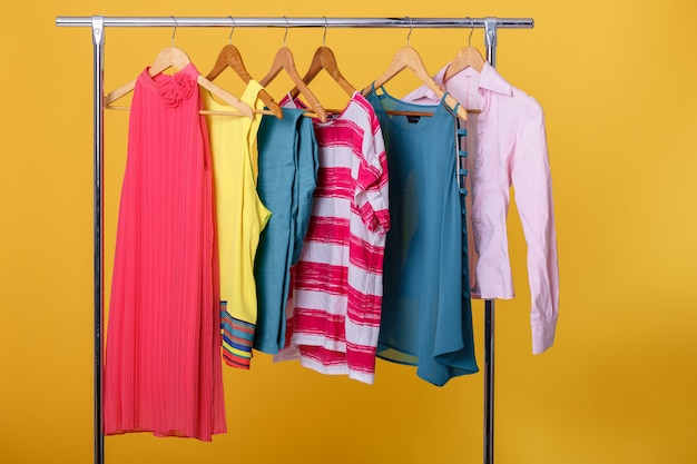 Colorful womens clothes on hangers on rack on orange