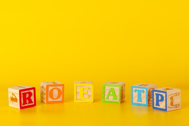 Colorful wooden blocks with letters on a yellow color background