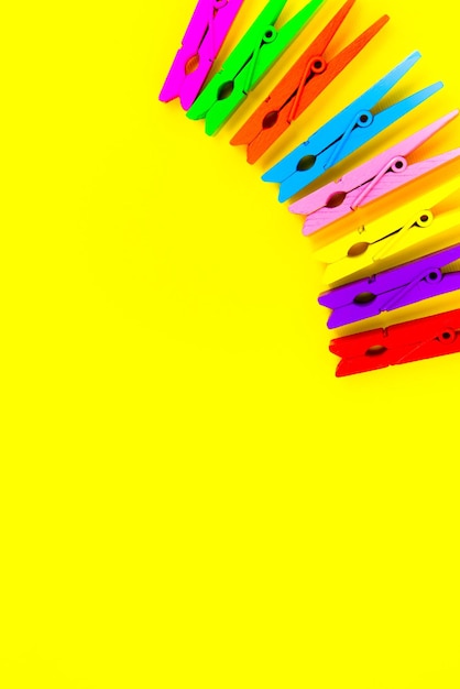 Colorful wooden clothespins on yellow background Close up copy space Minimalism original and creative photo Be another Individuality concept Vertical Wallpaper for smartphone