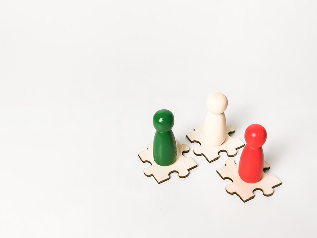 Colorful wooden figures on puzzle pieces. Collaboration concept.