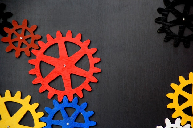 Colorful wooden gears on a black background. Space for text. A toy for children's development