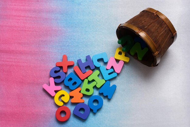 Colorful wooden letters in container on a colorful background