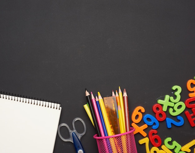 Colorful wooden pencils with notepads on chalkboard