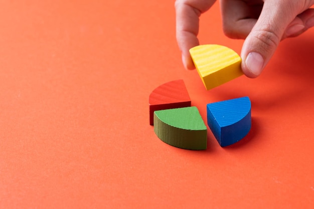Colorful wooden pie chart pieces fingers adding piece of diagram