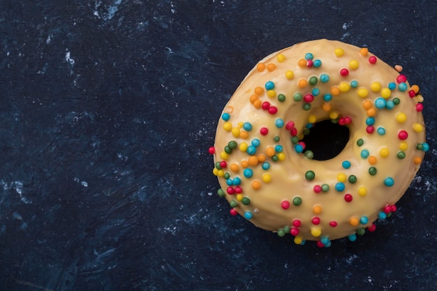 Colorful yellow donut on dark blue background Copyspace