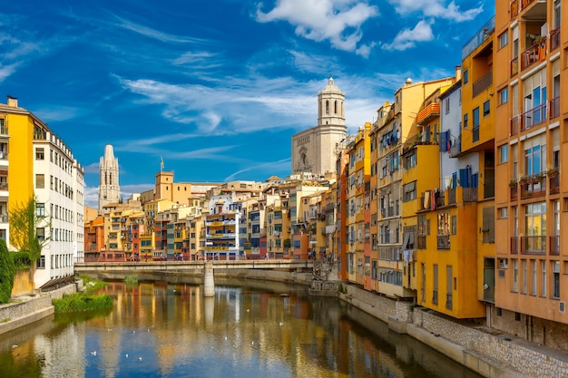 Colorful yellow and orange houses and bridge pont de sant agusti reflected in water river onyar in g...