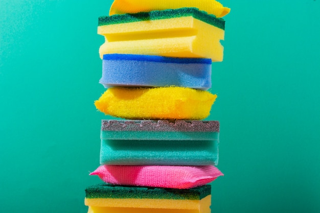 Colorful and yellow sponges for cleaning and washing dishes on green background