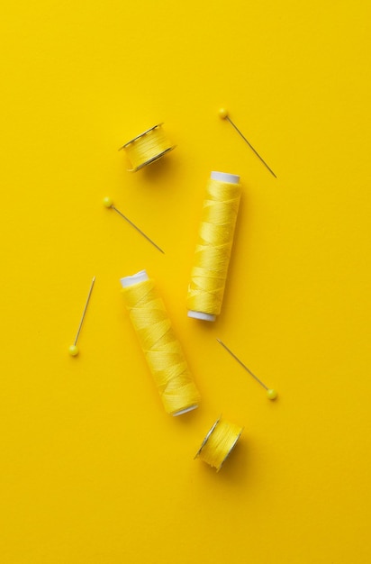 Colorful yellow thread spools over bright yellow background above view