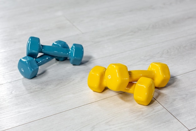 Colorfull modern dumbbells in the foreground on a wooden white floor