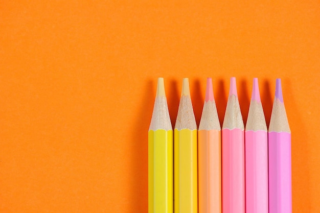 Colour pencils isolated on orange background close up