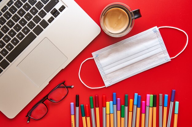 Coloured markers, mask and laptop on desk