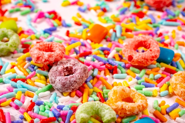 Colourful candy and sprinkles on light pink wood background