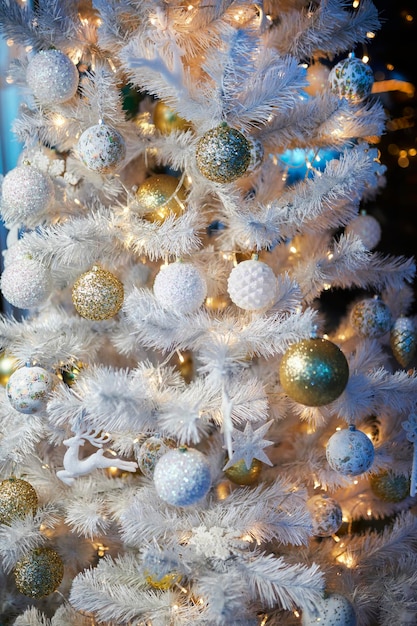 Colourful christmas decorations hanging from white christmas tree. white Christmas tree.