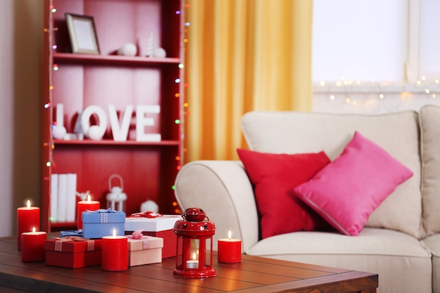 Colourful decorated interior. Comfortable living room, table with gift boxes and candles on it is close up