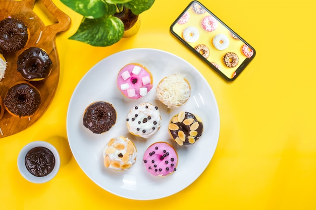 사진 노란색 배경에 흰색 접시에 화려한 도넛 제공