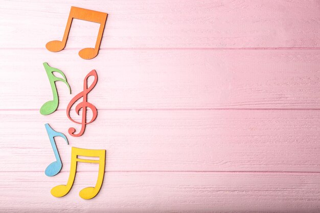 Photo colourful musical notes on pink wooden background