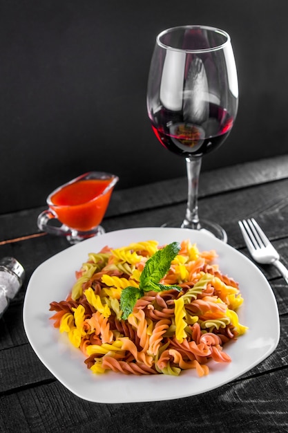 Pasta colorata con vino sul tavolo di legno nero