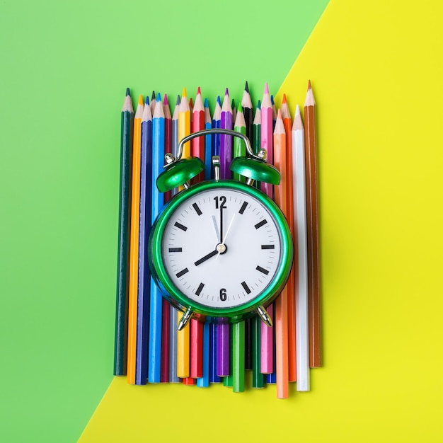 Colourful pencils and alarm clock Back to school concept