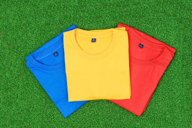 Colourful T-shirts on green grass background