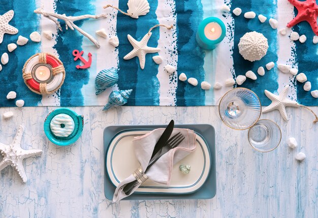 Columbus day lunch table setting with nautical sea decorations on blue stripy runner