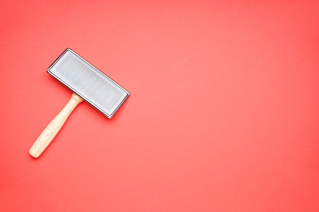 Comb for dogs on a red background, space for text. Brush for grooming wool. Flat lay.