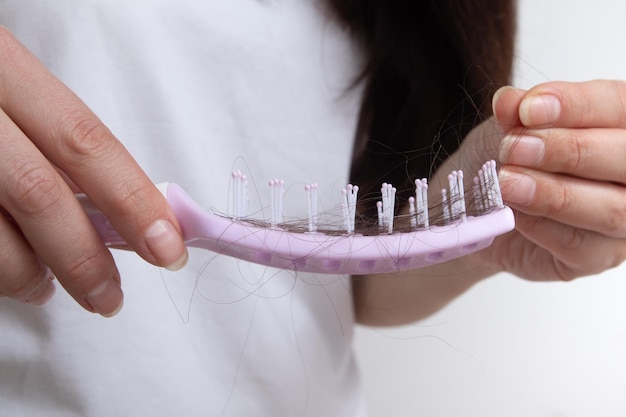 Comb in female hands with lost hair tangled and falling out hair care for long hair concept