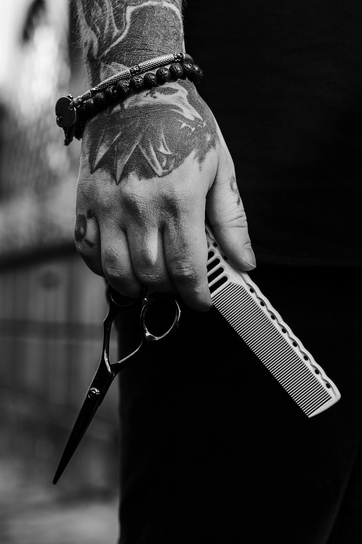Photo comb and a pair of scissors man is holdind in this tattooed hand