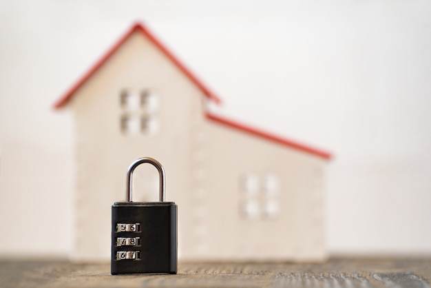 Combination lock and model home on blurred background. Home and security concept.