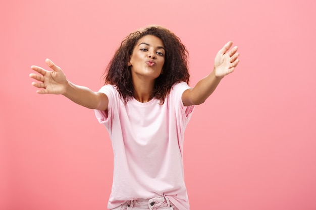 Come closer let me hug you portrait of passionate confident and happy goodlooking african american woman with curly hairstyle folding lips pulling hands towards to cuddle and give kiss