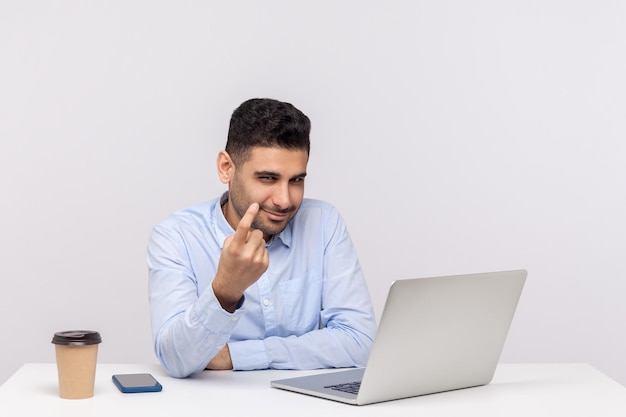 Vieni qui da me felice successo dipendente maschio hr manager seduto sul posto di lavoro dell'ufficio con il computer portatile che fa un gesto di cenno che invita a unirsi all'azienda indoor studio girato isolato su sfondo bianco