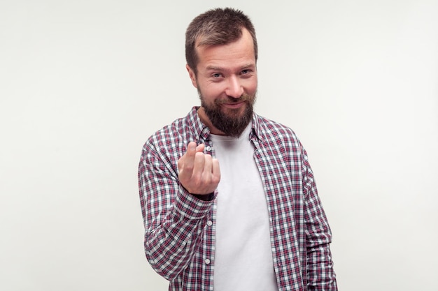 Photo come here sign. portrait of friendly bearded man in casual plaid shirt inviting to approach doing beckoning gesture and looking playful flirtatious. indoor studio shot isolated on white background