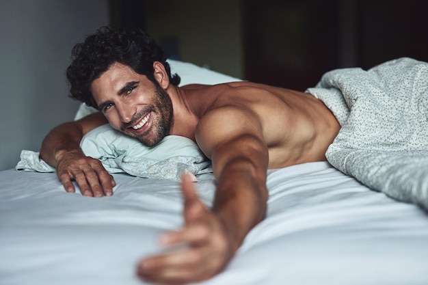 Come and join me Cropped shot of a handsome young shirtless man lying in bed at home