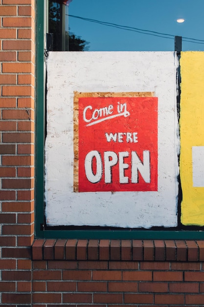 Photo come in were open hand painted restaurant sign in window brick wall covid-19 pandemic