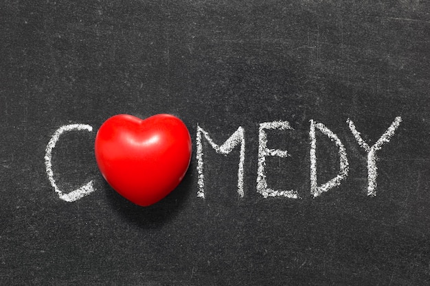 Comedy word handwritten on blackboard with heart symbol instead of O