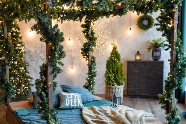 Comfort, interieur en vakantieconcept - gezellige slaapkamer met bed en Kerstmisslingerlichten thuis