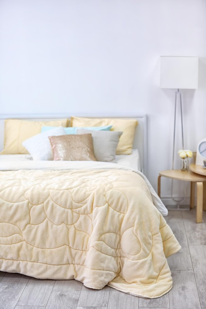 Comfortabel bed met sprei in licht slaapkamerinterieur