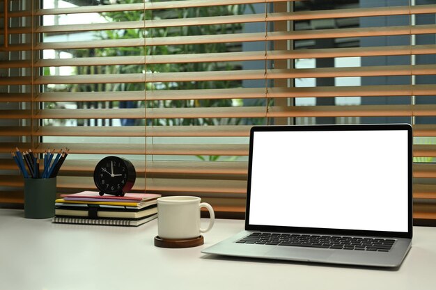 Comfortabel thuiskantoor met laptopcomputer koffiekopje en benodigdheden op witte tafel