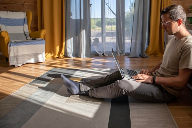 Comfortabel thuiswerken Een man zit en werkt op de vloer in een zonnig loft-appartement Thuiskantoor