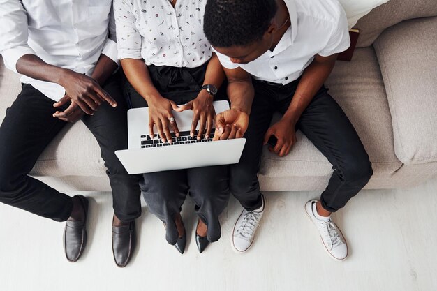 Comfortabele bank Met behulp van laptop Groep Afro-Amerikaanse zakenmensen die samen aan het werk zijn