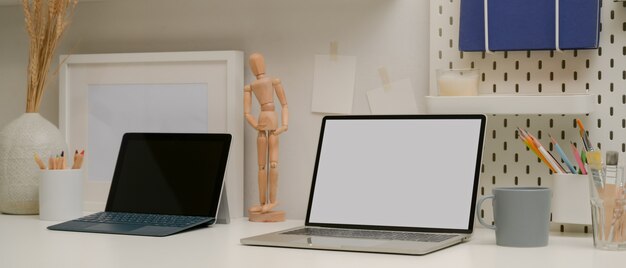 Comfortabele designwerkruimte met mock-up laptop, tablet met toetsenbord, benodigdheden en decoraties