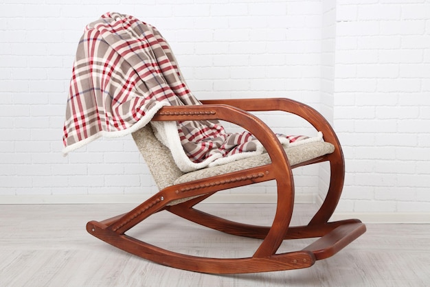 Comfortabele schommelstoel met tapijt op houten vloer dichtbij de bakstenen muurachtergrond