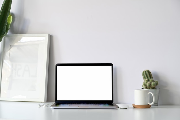 Foto comfortabele werkplaats met lege het schermlaptop computer en modelaffiche op de witte lijst van het bureaubureau