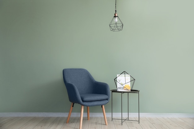 Comfortable armchair and table near color wall