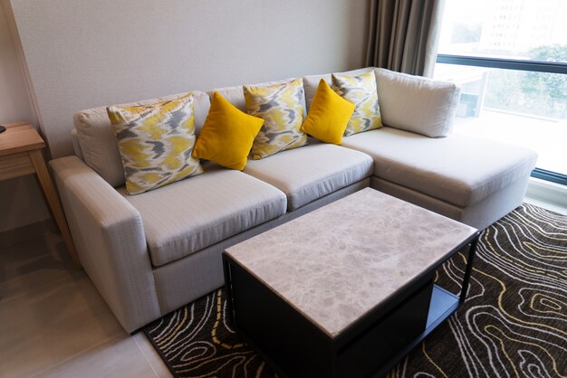 Comodo divano ad angolo con cuscini e tavolino da caffè sul tappeto nel soggiorno