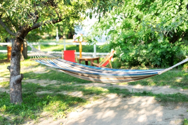 夏の庭の木にぶら下がっている快適なハンモック週末の居心地の良い場所庭でリラックス