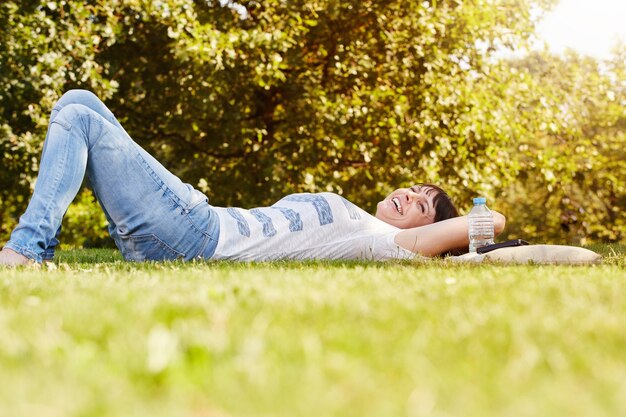 Comfortable happy woman lying in grass in autumn