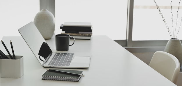 Photo comfortable office room with laptop computer and office supplies on white wooden table