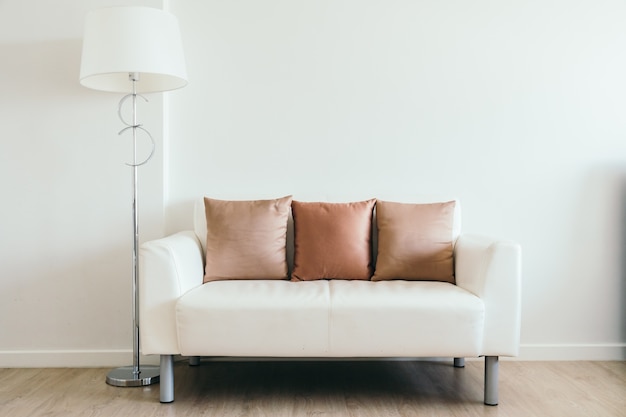 Comfortable pillow on white sofa with light lamp