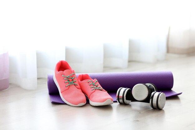 Comfortable sneakers with sport tools on floor